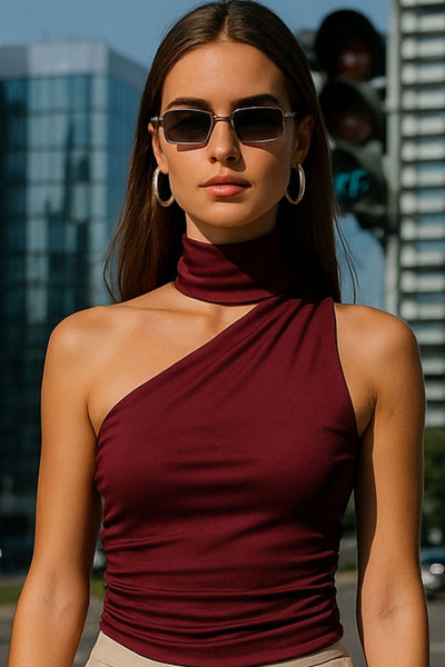 Top satinado asimétrico, de fit ajustado, detalles plisados laterales y en hombro, sin mangas, un hombro, escote diagonal y choker con plisados. Cierre posterior con botón y ojal.