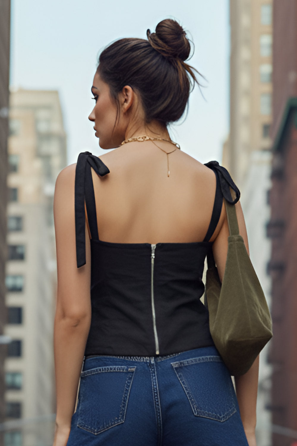 Crop top de fit ajustado, escote corazón con cortes decorativos, costuras frontales, tirantes con nudo amarrable y cierre posterior con cremallera visible en contraste.