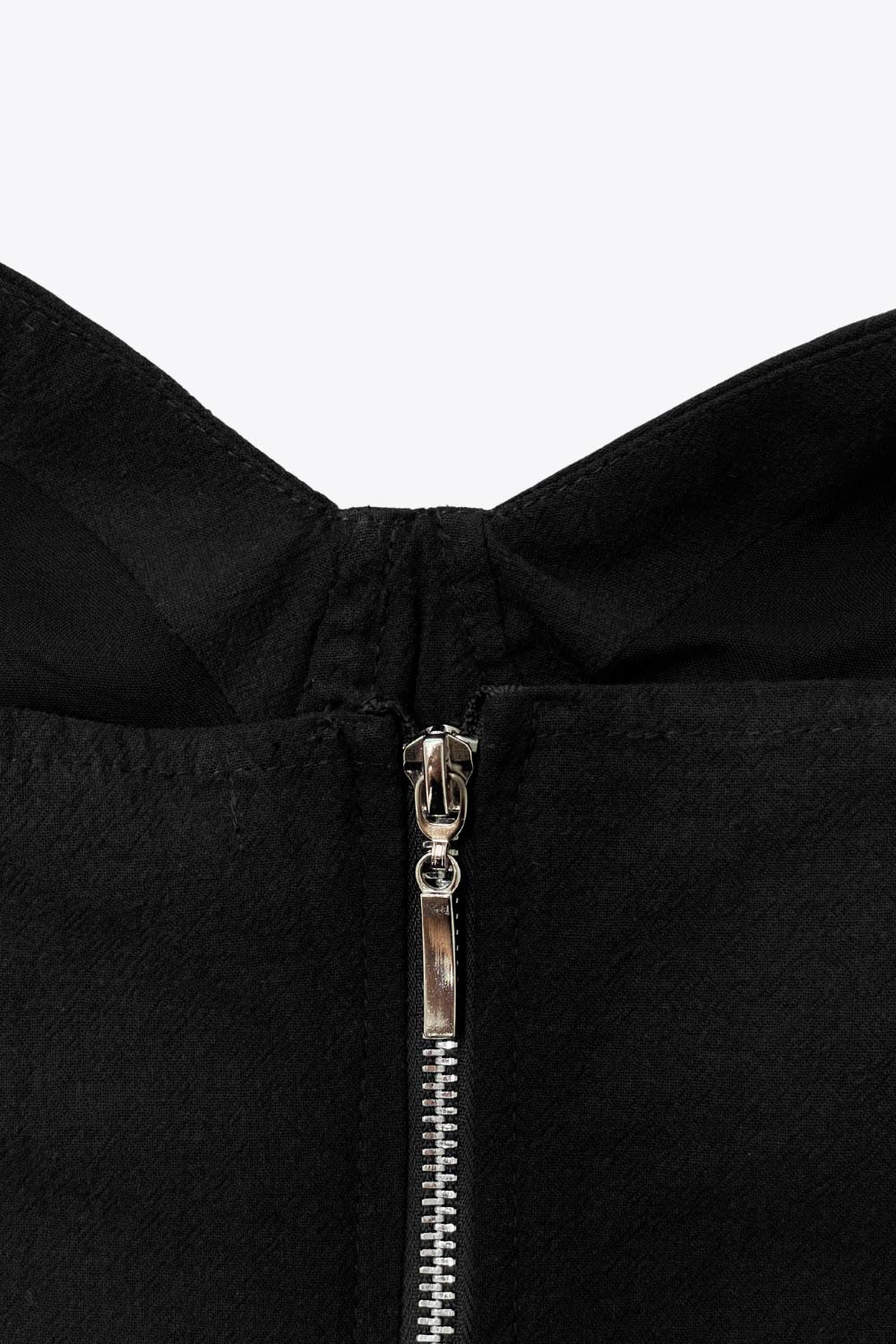 Crop top de fit ajustado, escote corazón con cortes decorativos, costuras frontales, tirantes con nudo amarrable y cierre posterior con cremallera visible en contraste.