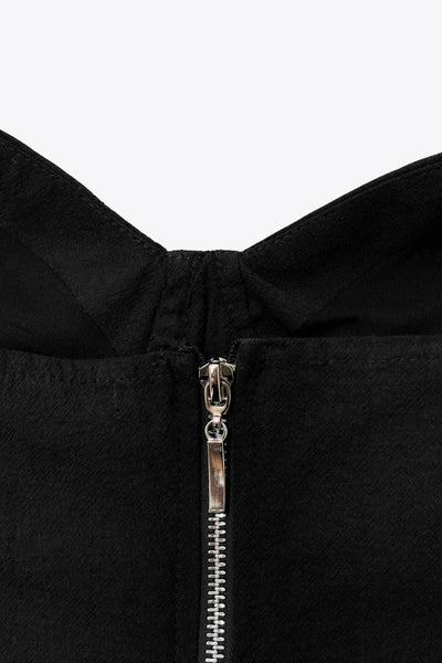 Crop top de fit ajustado, escote corazón con cortes decorativos, costuras frontales, tirantes con nudo amarrable y cierre posterior con cremallera visible en contraste.