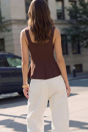 Top de fit ajustado, sin mangas, escote cuadrado, cortes frontales y peplum con olanes en bajo. Cierre frontal con hilera de botones en contraste.