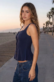 Top de fit ajustado, sin mangas, escote cuadrado, cortes frontales y peplum con olanes en bajo. Cierre frontal con hilera de botones en contraste.