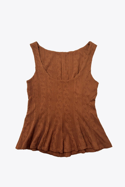 Top corto de peplum con olanes, cuello barco, escote en espalda, sin mangas, cortes frontales y detalle de textura en tejido.