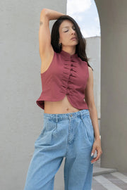 Top corto de fit ajustado, sin mangas, cuello mao, cierre frontal con botones y bajo frontal curveado.