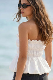 Top strapless con peplum globo, fit ajustado, escote recto con rib elástico y olanes en borde, plisados con rib elástico en cintura y bajo con acabado en volumen.
