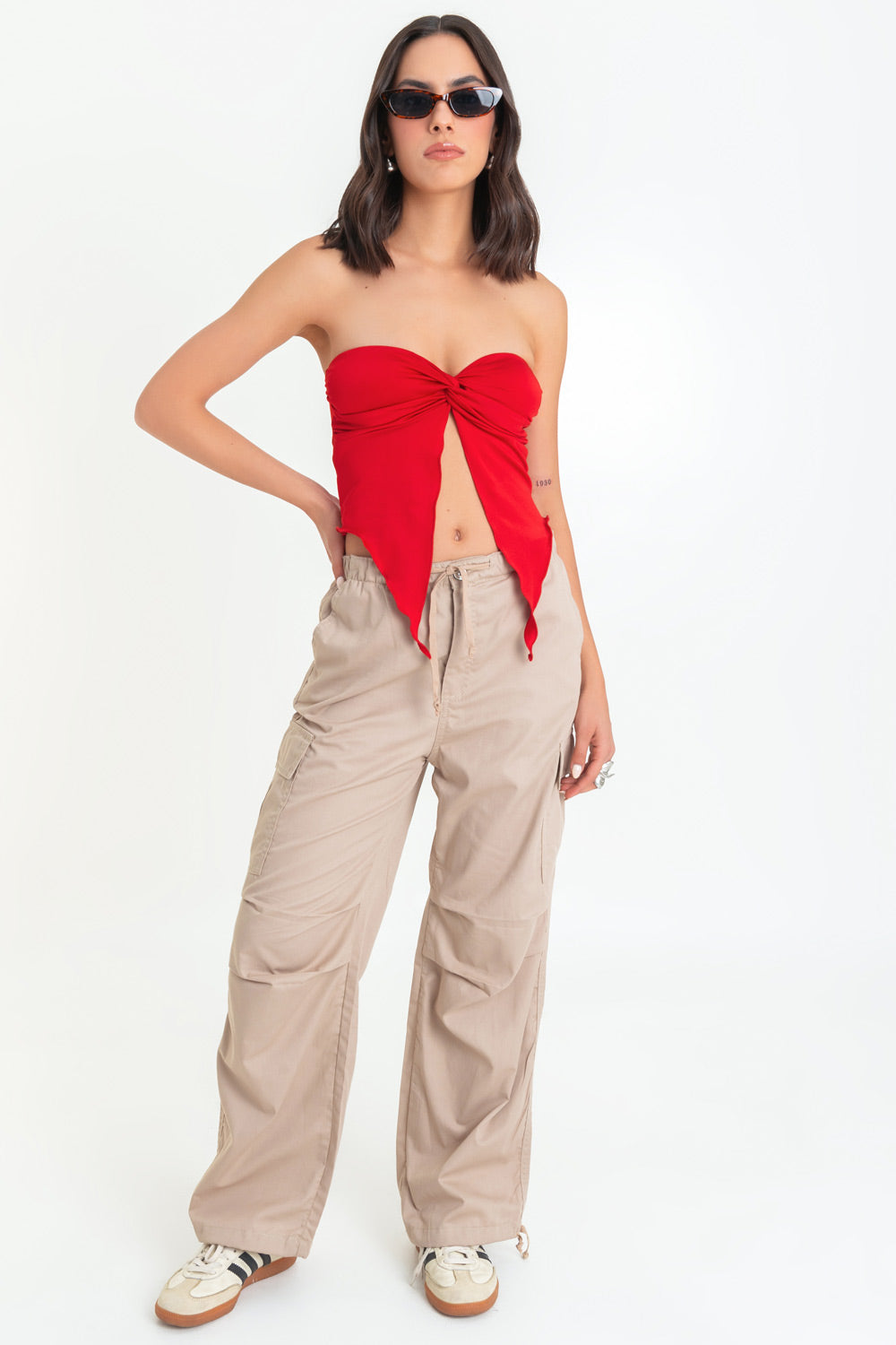 Top strapless satinado de escote corazón con nudo, plisados decorativos en costados y abertura frontal con bajo asimétrico. Rib rizado en borde de bajo.