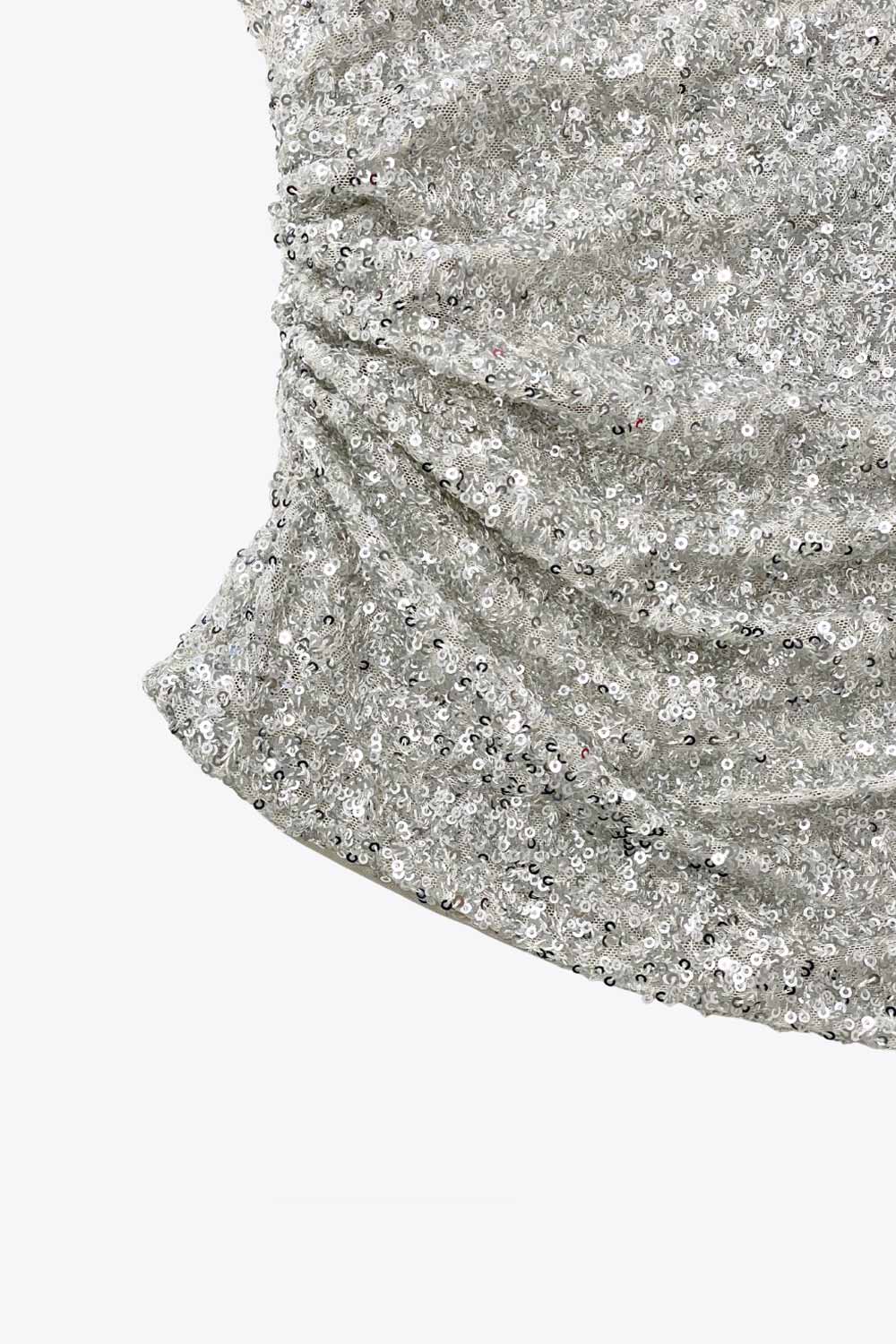 Top tubo de lentejuelas, fit ajustado, escote recto, plisados en costado y bajo diagonal asimétrico.