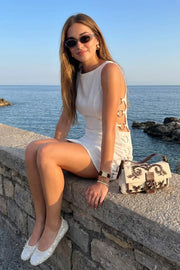 Vestido corto de fit ajustado, sin mangas, cuello barco, cut out en costados con argollas decorativas en contraste, costuras frontales y posteriores. Cierre posterior con cremallera oculta y detalle de escote en espalda.