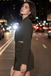 Vestido blazer corto cruzado de fit ajustado, manga larga, con hombreras y solapa. Cruce frontal con doble botón en contraste, bolsillos delanteros con cartera, vivo decorativo frontal y cut out en costados y espalda.