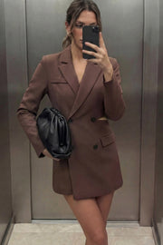 Vestido blazer corto cruzado de fit ajustado, manga larga, con hombreras y solapa. Cruce frontal con doble botón en contraste, bolsillos delanteros con cartera, vivo decorativo frontal y cut out en costados y espalda.