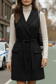 Vestido chaleco corto de fit recto, con solapa, bolsillos frontales con cartera, trabillas y cinturón amarrable del mismo tejido. Cierre frontal con doble cruce de botones.