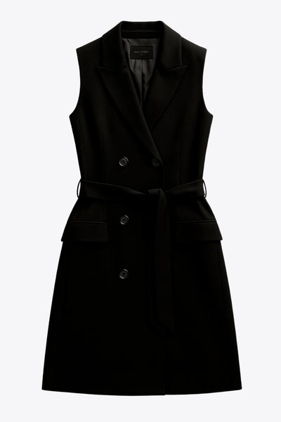 Vestido chaleco corto de fit recto, con solapa, bolsillos frontales con cartera, trabillas y cinturón amarrable del mismo tejido. Cierre frontal con doble cruce de botones.