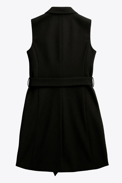 Vestido chaleco corto de fit recto, con solapa, bolsillos frontales con cartera, trabillas y cinturón amarrable del mismo tejido. Cierre frontal con doble cruce de botones.