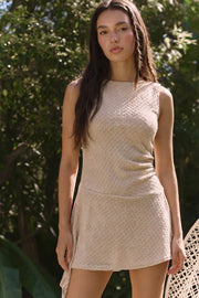 Vestido corto de fit ajustado, cuello redondo, sin mangas, corte en cadera, plisados en costado y bajo asimétrico. Detalle de escote en espalda y textura en tejido.