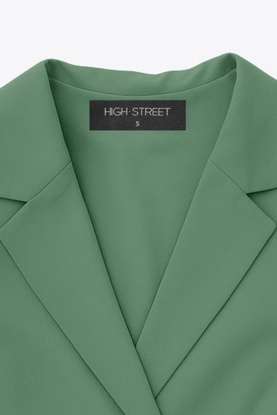 Vestido corto cruzado tipo blazer, fit ajustado, de manga larga abullonada con puño abotonado, solapa, doble cruce de botones y bajo con olanes en borde.