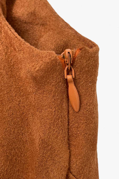 Vestido corto de gamuza, cuello barco, sin mangas, cortes frontales, escote en espalda y corte en a con olanes en bajo. Cierre lateral con cremallera oculta.