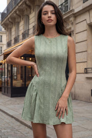 Vestido corto de encaje, fit ajustado, sin mangas, cuello redondo, corte en a con plisados laterales y olanes en bajo. Cierre posterior con cremallera oculta.