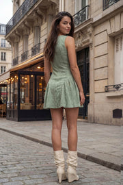 Vestido corto de encaje, fit ajustado, sin mangas, cuello redondo, corte en a con plisados laterales y olanes en bajo. Cierre posterior con cremallera oculta.