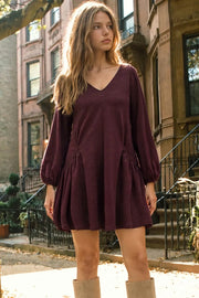 Vestido corto de fit fluido, escote v, manga 3/4 abullonada con rib elástico en puños y plisados decorativos laterales con elástico.