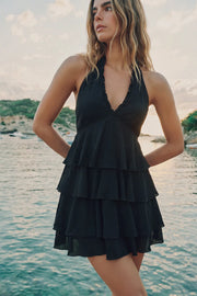 Vestido corto de cuello halter con nudo amarrable posterior, escote v con cortes y plisados decorativos, corte en a&nbsp; y capas de olanes en bajo. Escote en espalda y cierre posterior con cremallera oculta.