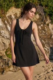 Vestido corto de corte en a, sin mangas, escote v con cortes y lazo decorativo frontal.