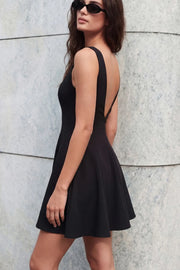 Vestido corto de corte en a, cuello barco, sin mangas, pinzas frontales con cortes y olanes en bajo. Detalle de escote en espalda.