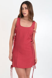 Vestido corto de fit recto, sin mangas, escote redondeado, cut out en costados con lazos amarrables decorativos y cierre posterior con cremallera oculta.