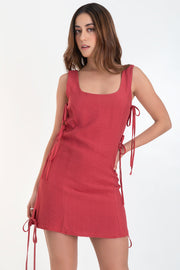 Vestido corto de fit recto, sin mangas, escote redondeado, cut out en costados con lazos amarrables decorativos y cierre posterior con cremallera oculta.