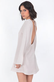 Vestido corto de fit recto, cuello barco, manga larga con puño amplio, escote en espalda y lazo amarrable posterior.