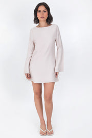 Vestido corto de fit recto, cuello barco, manga larga con puño amplio, escote en espalda y lazo amarrable posterior.