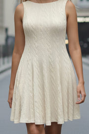Vestido corto de cuello barco, sin mangas, pinzas frontales, escote en espalda y corte en a con olanes en bajo. Detalle de textura en tejido.
