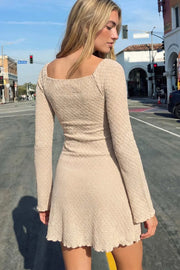 Vestido corto de escote corazón con cortes y plisados decorativos frontales, manga larga con puño amplio y corte en a. Detalle de textura en tejido y rib rizado en bajo.