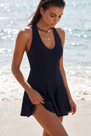 Vestido corto canalé, de fit ajustado, escote v, sin mangas, pinzas frontales, corte en a y olanes en bajo. Cierre posterior con cremallera oculta.