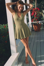 Vestido corto canalé, de fit ajustado, escote v, sin mangas, pinzas frontales, corte en a y olanes en bajo. Cierre posterior con cremallera oculta.