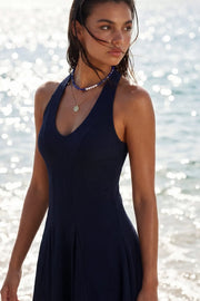 Vestido corto canalé, de fit ajustado, escote v, sin mangas, pinzas frontales, corte en a y olanes en bajo. Cierre posterior con cremallera oculta.