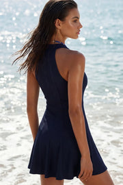 Vestido corto canalé, de fit ajustado, escote v, sin mangas, pinzas frontales, corte en a y olanes en bajo. Cierre posterior con cremallera oculta.