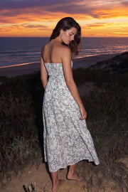 Vestido midi strapless de estampado floral, escote corazón con nudo amarrable, cut out frontal, cintura elástica, detalle de capas de olanes en bajo y fruncido en espalda.