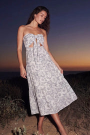 Vestido midi strapless de estampado floral, escote corazón con nudo amarrable, cut out frontal, cintura elástica, detalle de capas de olanes en bajo y fruncido en espalda.