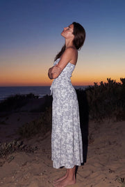 Vestido midi strapless de estampado floral, escote corazón con nudo amarrable, cut out frontal, cintura elástica, detalle de capas de olanes en bajo y fruncido en espalda.