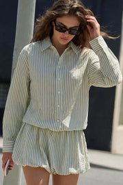 Vestido camisero, de falda corta globo, estampado rayas, cuello camisero, manga larga con puño abotonado, fit recto, bajo con acabado en volumen y plisados en cadera. Cierre frontal con hilera de botones.