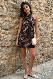 Vestido corto de estampado animal, fit fluido, cuello halter fluido con plisados y nudo amarrable posterior. Detalle de plisados en costado y escote en espalda.