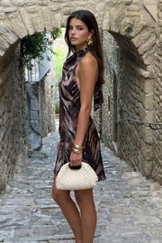 Vestido corto de estampado animal, fit fluido, cuello halter fluido con plisados y nudo amarrable posterior. Detalle de plisados en costado y escote en espalda.