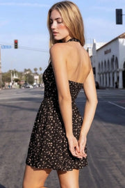 Vestido corto de estampado floral, cuello halter con rib elástico, sin mangas, escote recto, cortes frontales, detalle frontal v en cintura con plisados y fruncido en espalda.