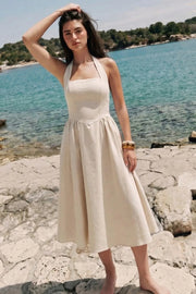 Vestido midi de lino, cuello halter, sin mangas, escote recto, corte en a, corte v en cintura con plisados y fruncido en espalda.