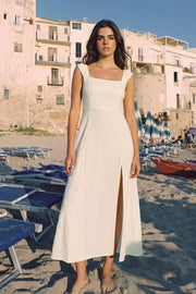 Vestido largo de fit recto, escote redondeado, corte frontal, tirantes elásticos con plisados y escote en espalda con lazado ajustable. Abertura frontal en bajo, rib elástico y cremallera oculta posterior.