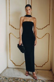 Vestido largo strapless, de fit ajustado, escote recto, cierre posterior con cremallera visible en contraste y abertura en bajo. Detalle decorativo de choker.