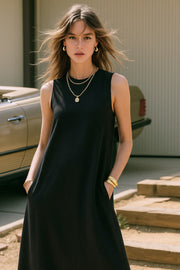 Vestido midi básico de fit fluido, corte en a, sin mangas, bolsillos delanteros y cuello redondo. Cierre posterior con botón y ojal.