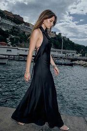 Vestido largo de fit fluido, cuello alto halter fluido, sin mangas, escote en espalda y lazo amarrable posterior.