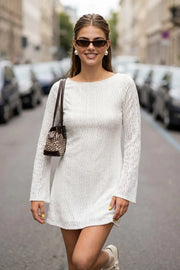 Vestido corto de crochet, manga larga con puño amplio, corte en a, cuello barco y escote en espalda con lazo amarrable posterior.