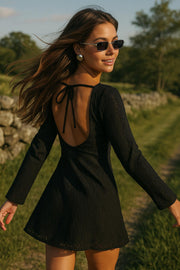 Vestido corto de crochet, manga larga con puño amplio, corte en a, cuello barco y escote en espalda con lazo amarrable posterior.